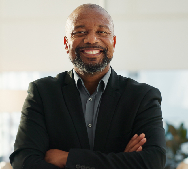 A photo of a man smiling broadly with his arms crossed