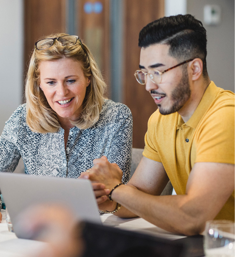 A woman and a man work together on a laptop